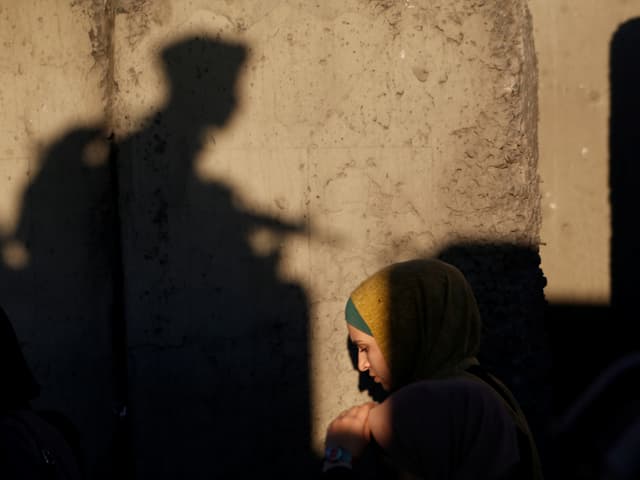 Palästinenserin in der Altstadt von Jerusalem, dahinter der Schatten eines Soldaten. Palästinenserin in der Altstadt von Jerusalem, dahinter der Schatten eines Soldaten.