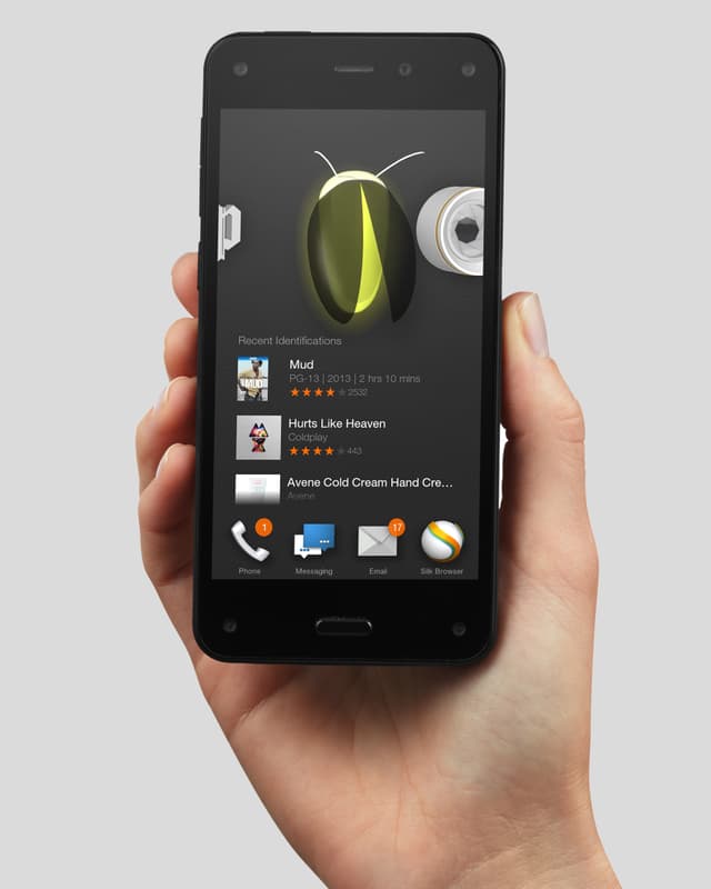 Eine Hand hält ein Fire Phone mit der Firefly-Funktion in die Höhe. Eine Hand hält ein Fire Phone mit der Firefly-Funktion in die Höhe.