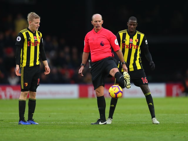 Die beiden Watford-Spieler Will Hughes und Abdoulaye Doucoure staunen über die Ballkontrolle von Schiedsrichter Mike Dean.