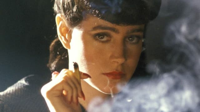 Filmszene: eine Frau raucht eine Zigarette und schaut in die Kamera Filmszene: eine Frau raucht eine Zigarette und schaut in die Kamera