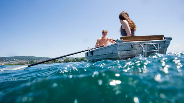 Nico und Claudia geniessen das schöne Wetter auf einem Ruderboot auf dem Zürichsee in. (keystone)