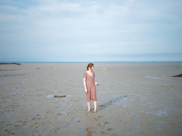 Eine Frau steht barfuss am Strand und schaut wirr umher. Eine Frau steht barfuss am Strand und schaut wirr umher.