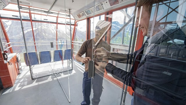 Zwei Männer montieren in der Gondel Plexiglasscheiben. Zwei Männer montieren in der Gondel Plexiglasscheiben.