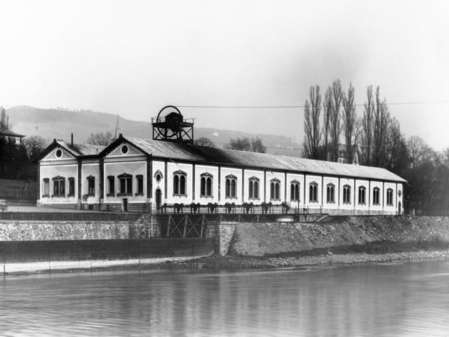 Die Sihl im Vordergrund, im Hintergrund das EWZ Letten - ein langes, einstöckiges Haus, schwarz-weiss. Die Sihl im Vordergrund, im Hintergrund das EWZ Letten - ein langes, einstöckiges Haus, schwarz-weiss.