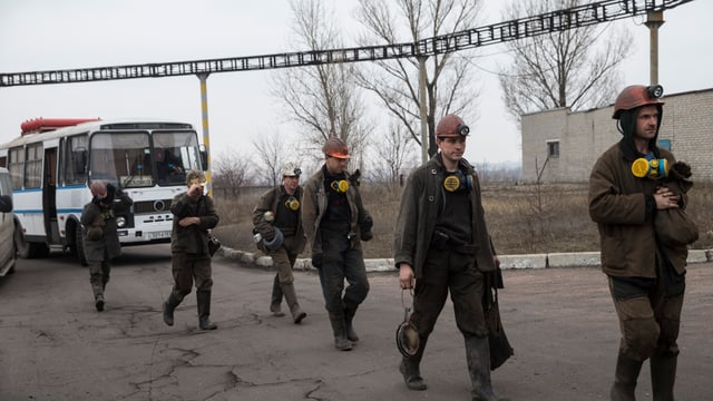 Helfer sind aus dem Bus ausgestiegen und marschieren auf die Mine zu. Helfer sind aus dem Bus ausgestiegen und marschieren auf die Mine zu.