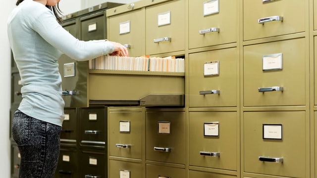 Eine Frau vor einem Schrank mit vielen Dossier. Eine Frau vor einem Schrank mit vielen Dossier.