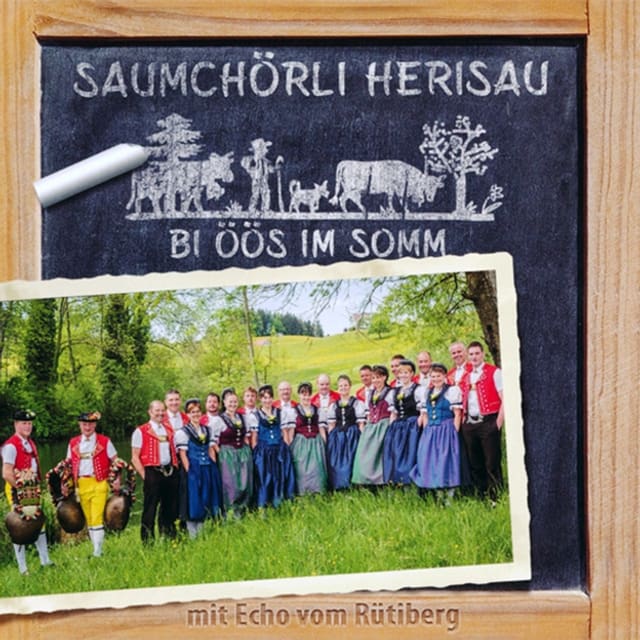 Eine Schiefertafel auf der ein Foto des Jodelchors liegt. Eine Schiefertafel auf der ein Foto des Jodelchors liegt.