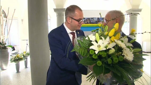 Ein Mann übergibt einem anderen Blumen. Ein Mann übergibt einem anderen Blumen.