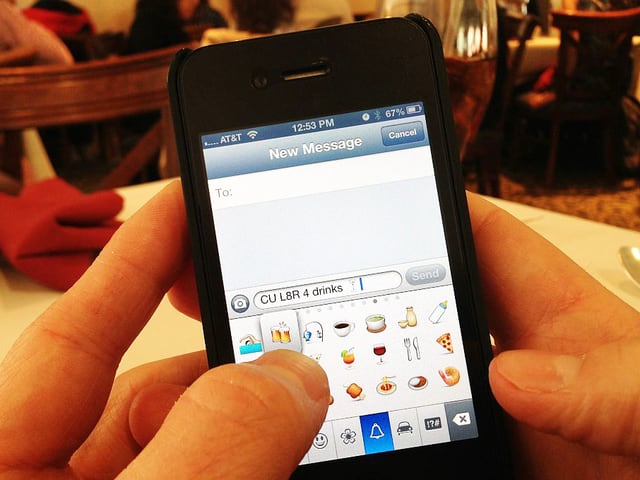 Jemand schreibt eine Textnachricht. Auf dem Bildschirm sind Emojis angezeigt. Jemand schreibt eine Textnachricht. Auf dem Bildschirm sind Emojis angezeigt.