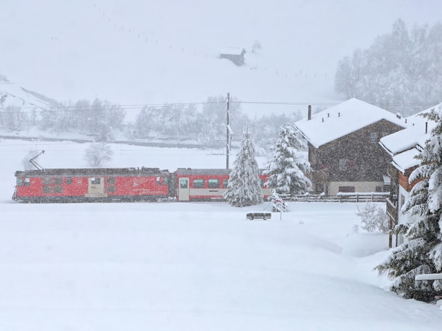 Roter Zug in weisser Winterlandschaft.