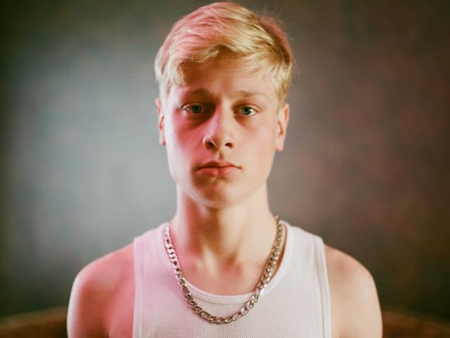 Ein Junge mit kurzem, blondem Haar, einem weissen Tank-Top und eine Goldkette. Ein Junge mit kurzem, blondem Haar, einem weissen Tank-Top und eine Goldkette.