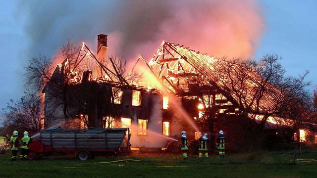 Feuerwehrleute versuchen einen brennenden Bauernhof zu löschen. Feuerwehrleute versuchen einen brennenden Bauernhof zu löschen.