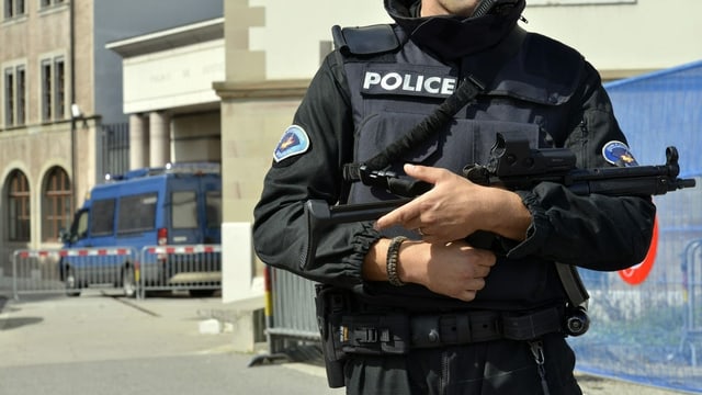 Genfer Polizist mit Schutzweste und Maschinenpistole in der Nähe eines Gerichtsgebäudes Genfer Polizist mit Schutzweste und Maschinenpistole in der Nähe eines Gerichtsgebäudes
