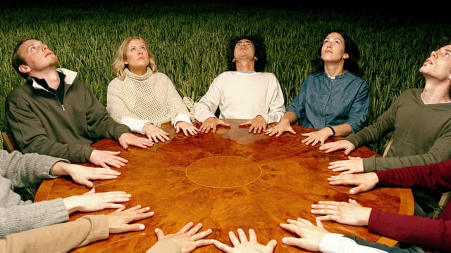 Menschen sitzen im Kreis um einen Tisch bei einer Séance Menschen sitzen im Kreis um einen Tisch bei einer Séance