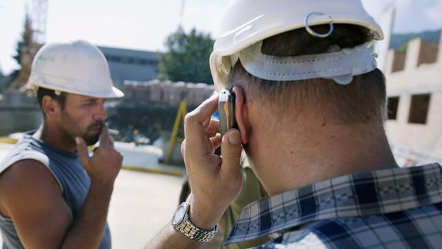 Zwie Bauarbeiter mit Helm, einer hat Handy am Ohr Zwie Bauarbeiter mit Helm, einer hat Handy am Ohr