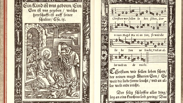 Aufgeschlagenes Gesangbuch: rechte Seite ein Bild einer Frau und eines Mannes mit Baby, linke Seite Noten mit Text. Aufgeschlagenes Gesangbuch: rechte Seite ein Bild einer Frau und eines Mannes mit Baby, linke Seite Noten mit Text.