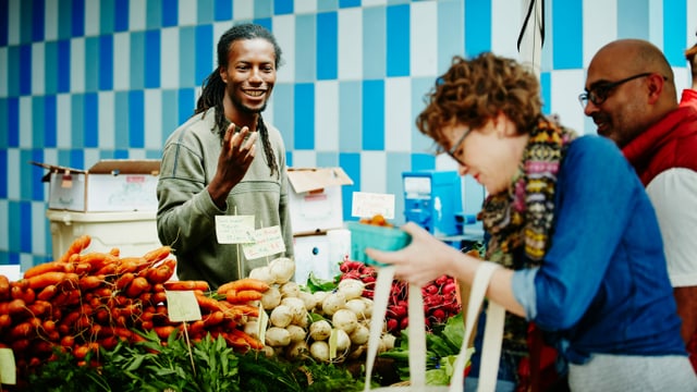 Marktstand mit Verkäufer und einer bunten Auslage von frischem Gemüse. Marktstand mit Verkäufer und einer bunten Auslage von frischem Gemüse.
