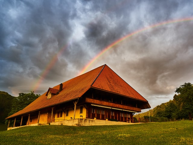 Regenbogen hinter Haus.
