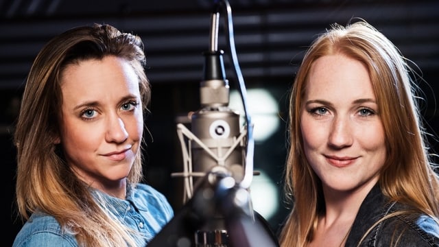 Anna Känzig und Ira May stehen bei einem Mikrophon. Anna Känzig und Ira May stehen bei einem Mikrophon.
