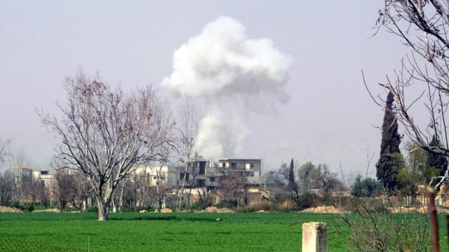 Ein Haus in der Ferne, dahinter eine aufsteigende Rauchwolke nach einem Bombeneinschlag. Ein Haus in der Ferne, dahinter eine aufsteigende Rauchwolke nach einem Bombeneinschlag.