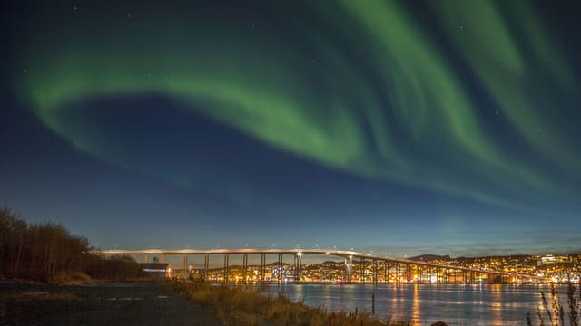 Nordlichter über einer Stadt mit Brücke über das Wasser. Nordlichter über einer Stadt mit Brücke über das Wasser.