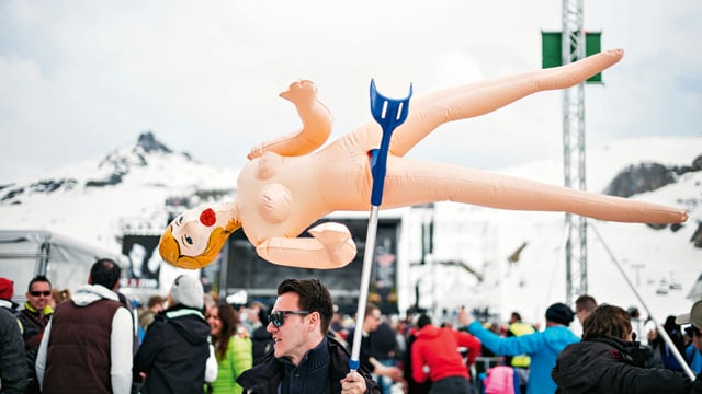 ein Mann hält mit einer Krücke eine Gummipuppe hoch ein Mann hält mit einer Krücke eine Gummipuppe hoch