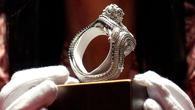 Behandschuhte Hände zeigen ein silbernes Luxus-Schmuckstück Behandschuhte Hände zeigen ein silbernes Luxus-Schmuckstück