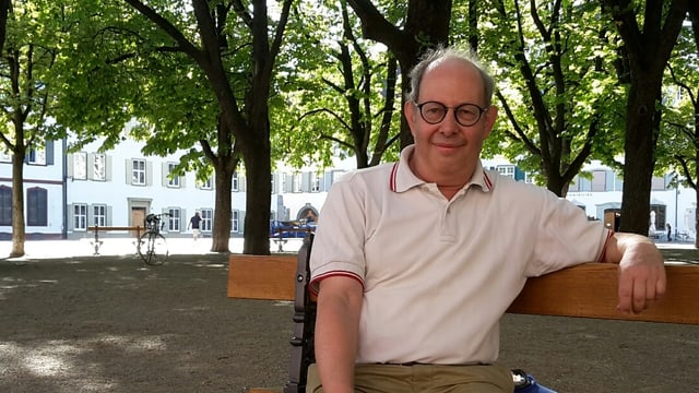Mann sitzt auf einer Bank unter Bäumen. Mann sitzt auf einer Bank unter Bäumen.