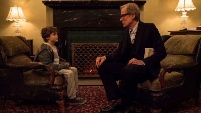 Bill Nighy sitzt auf einem Sessel. Neben ihm sitzt ein kleiner Junge auf einem Sessel. Bill Nighy sitzt auf einem Sessel. Neben ihm sitzt ein kleiner Junge auf einem Sessel.