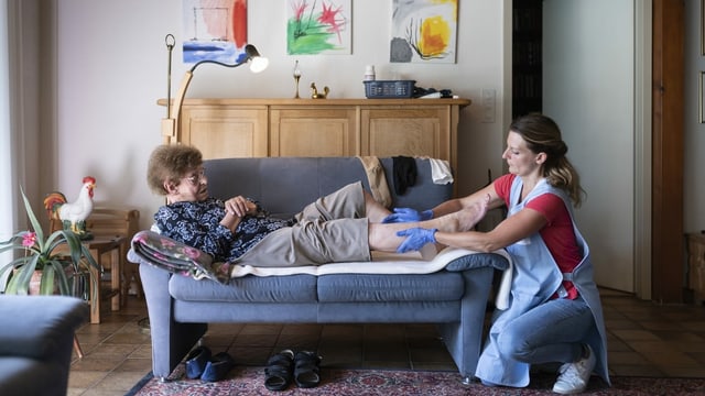 Spitex-Pflegefrau massiert das Bein einer Seniorin Spitex-Pflegefrau massiert das Bein einer Seniorin