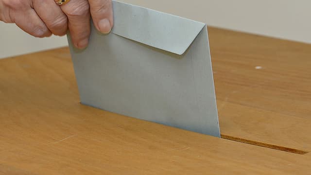 Wahlcouvert in Urne einwerfen Wahlcouvert in Urne einwerfen