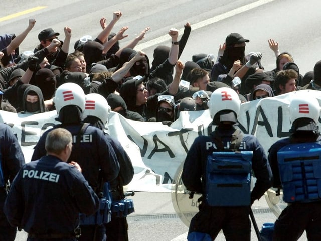 Der «Schwarze Block» 2005 in Zürich, davor Polizisten in Vollmontur. Der «Schwarze Block» 2005 in Zürich, davor Polizisten in Vollmontur.