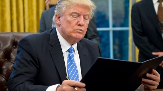 Trump verzieht das Gesicht und hält eine Akte in der Hand Trump verzieht das Gesicht und hält eine Akte in der Hand