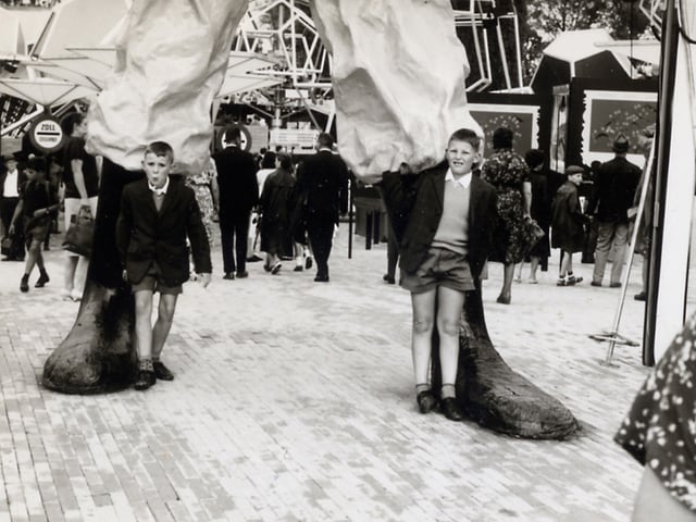 Schwarz-Weiss Fotografie mit zwei Buben, die neben den Füssen des Riesen Gulliver stehen. Schwarz-Weiss Fotografie mit zwei Buben, die neben den Füssen des Riesen Gulliver stehen.