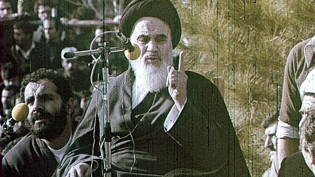 Ajatollah Chomeini steht am Mikrofon und hält eine Rede. Ajatollah Chomeini steht am Mikrofon und hält eine Rede.