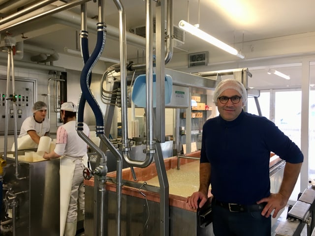 Der Käser steht vor einem grossen Kessel, mit flüssigem Käse drin. Der Käser steht vor einem grossen Kessel, mit flüssigem Käse drin.