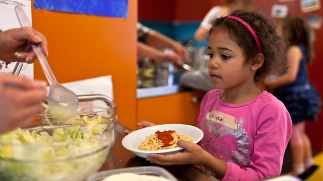 Eine Kinderkrippe in Zürich, ein Kind holt sich ein Teller Teigwaren. Eine Kinderkrippe in Zürich, ein Kind holt sich ein Teller Teigwaren.