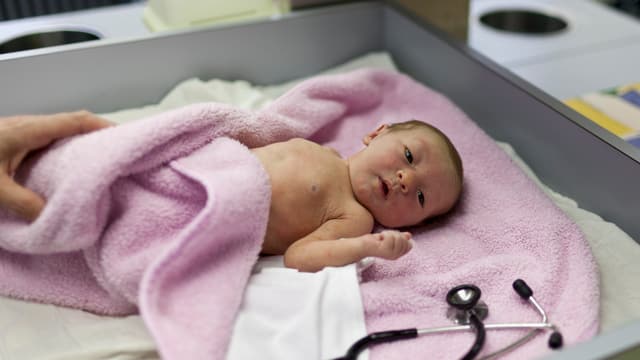 Ein Neugeborenes, eingewickelt in einer rosa Decke.