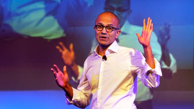 Satya Nadella in weissem Hemd vor einer Leinwand Satya Nadella in weissem Hemd vor einer Leinwand