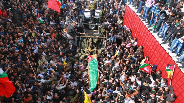 Demonstranten tragen verhüllten Leichnam.