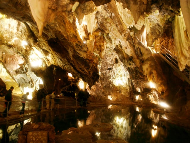 Beleuchtete, grosse Höhle, von welcher Tropfsteine herunterhängen. Beleuchtete, grosse Höhle, von welcher Tropfsteine herunterhängen.