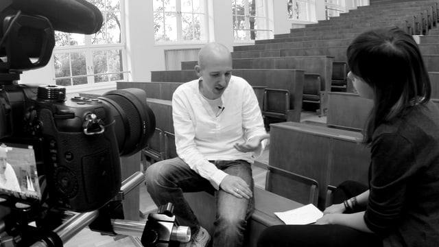 Schwarz-weiss Bild mit Reporterin, Interviewpartner und Kamera im Bild. Schwarz-weiss Bild mit Reporterin, Interviewpartner und Kamera im Bild.