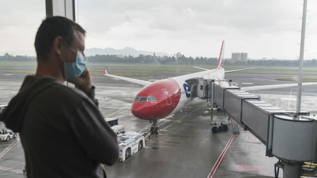 Mann mit Maske vor Flugzeug Mann mit Maske vor Flugzeug