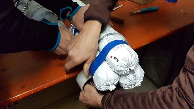 Drei weisse "Würste" werden mit Klebeband zusammengeklebt. Drei weisse "Würste" werden mit Klebeband zusammengeklebt.