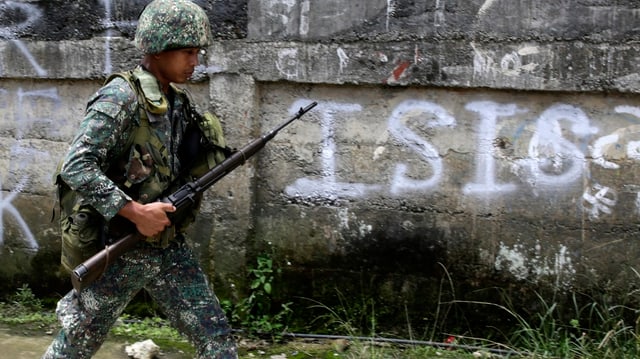 Soldat geht an einem Schriftzug «ISIS» vorbei. Soldat geht an einem Schriftzug «ISIS» vorbei.