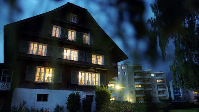 Altes Holzhaus mit hell beleuchteten Fenstern vor dunklem Nachthimmel. Altes Holzhaus mit hell beleuchteten Fenstern vor dunklem Nachthimmel.