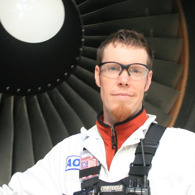 Sean Riley vor einer Turbine eines Flugzeugs. Sean Riley vor einer Turbine eines Flugzeugs.