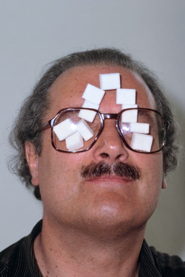 Der Schweizer Künstler André Thomkins steckt sich in einer Pause während des Aufbaus seiner Ausstellung, Zuckerstücke hinter die Brillengläser. Städtische Galerie zum Strauhof, Zürich, 9. Juni 1982. Der Schweizer Künstler André Thomkins steckt sich in einer Pause während des Aufbaus seiner Ausstellung, Zuckerstücke hinter die Brillengläser. Städtische Galerie zum Strauhof, Zürich, 9. Juni 1982.