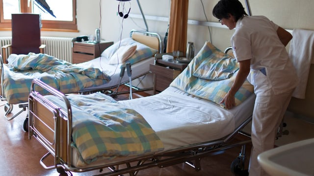 Eine Pflegerin richtet ein Patientenbett her