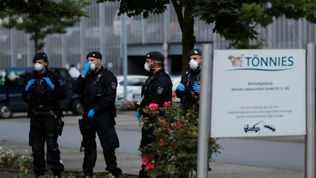 Polizisten mit Gesichtsmaske vor dem Tönnies-Betriebsgebäude. Polizisten mit Gesichtsmaske vor dem Tönnies-Betriebsgebäude.